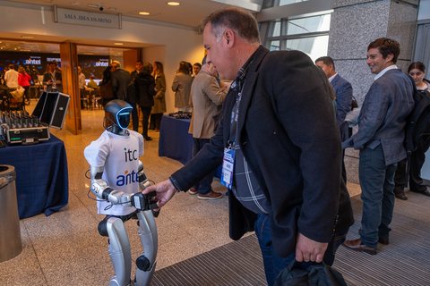 Un robot humanoide con la remera de ITC y Antel recibe a los asistentes